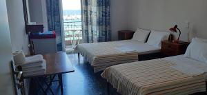 Habitación de hotel con 2 camas, mesa y ventana en Myrto, en Tyros