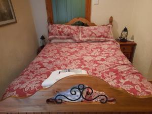 a bed with a red comforter with a pair of shoes on it at Moira Barn At Berwickhall in Moira