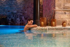 a woman is sitting in a swimming pool at Hotel Helvetia Thermal SPA 4s in Porretta Terme