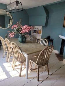 a dining room table with chairs and a vase of flowers at A Unique Cottage in the centre of Cley in Cley next the Sea