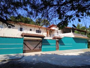 a blue and white building with a gate at Chalés Bielle de Ubatuba in Ubatuba