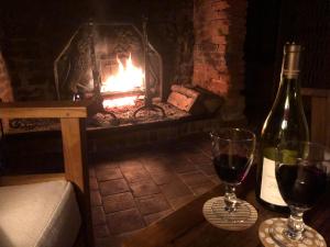 a bottle of wine and two glasses in front of a fireplace at Cottage les forières in Saint-Honoré