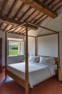 a bedroom with a canopy bed with a window at Bioagriturismo il cerreto in Pomarance