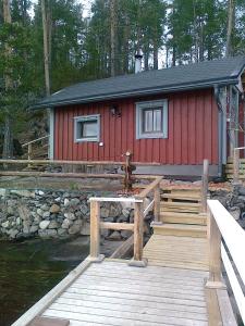 a red cabin with a wooden dock next to the water at Rantakallio Savonlinna, Tervetuloa meille! in Savonlinna
