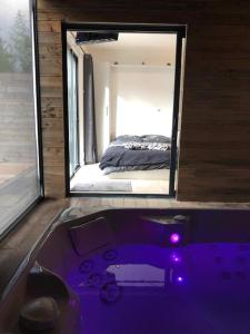 a bathroom with a purple bath tub in front of a bedroom at Loft privatisé avec spa XXL et piscine chauffée in Bruz