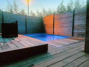 a small swimming pool on a wooden deck with a tv at Loft privatisé avec spa XXL et piscine chauffée in Bruz