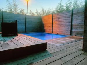 una pequeña piscina en una terraza de madera con TV en Loft privatisé avec spa XXL et piscine chauffée, en Bruz