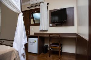 a bedroom with a desk with a tv and a chair at Hotel Premium in Gramado