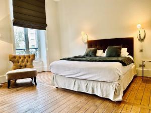 1 dormitorio con 1 cama grande y 1 silla en La Villa Beaupeyrat - Apparthôtels de charme dans bâtisse de caractère, en Limoges