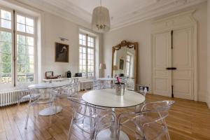 een eetkamer met stoelen, een tafel en een spiegel bij La Villa Beaupeyrat - Apparthôtels de charme dans bâtisse de caractère in Limoges