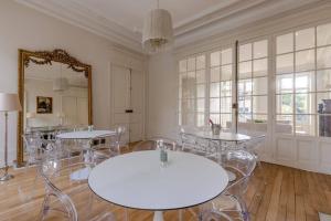 Cette chambre comprend une table, des chaises et un miroir. dans l'établissement La Villa Beaupeyrat - Apparthôtels de charme dans bâtisse de caractère, à Limoges