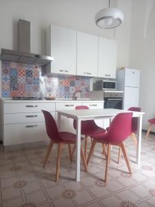 cocina con mesa blanca y sillas rosas en Liberty Apartment, en Galatone