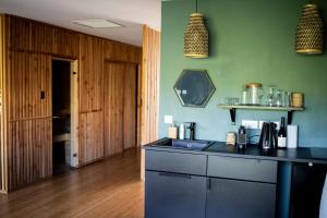 eine Küche mit einer schwarzen Arbeitsplatte und grünen Wänden in der Unterkunft L ABRI spa et détente in Liergues