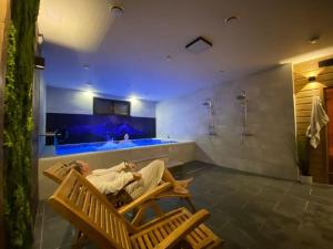 a man laying in a chair in a bathroom with a tub at Chalupa Grúnik in Jezersko