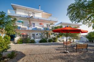 einem Tisch mit einem Regenschirm vor einem Gebäude in der Unterkunft Salora Studio-Apartments in Archangelos