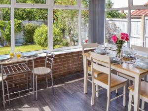 uma sala de jantar com mesas, cadeiras e janelas em Peace Haven em Gorleston-on-Sea