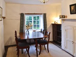 een eetkamer met een tafel en stoelen en een raam bij The Old Post Office in Yellowham Wood