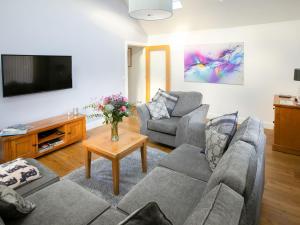 a living room with two couches and a tv at Rossie Cottage in Auchterarder