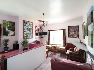 un soggiorno con pareti rosa, divano e sedie di T Melindwr a Capel Bangor