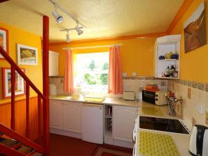 a kitchen with orange walls and white cabinets and a window at T Melindwr in Capel Bangor