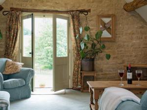 ein Wohnzimmer mit einem Sofa und einem Tisch mit Weingläsern in der Unterkunft Flowers Barn in Daglingworth