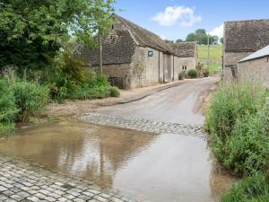 uma velha estrada com água numa aldeia em Flowers Barn em Daglingworth