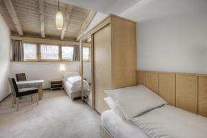 1 dormitorio con cama, escritorio y silla en Hotel La Tambra, en Corvara in Badia