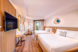a hotel room with two beds and a flat screen tv at Belek Beach Resort Hotel in Belek