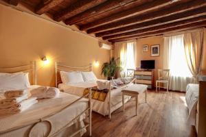 a bedroom with two beds and a desk and a television at Ca' Riza in Venice