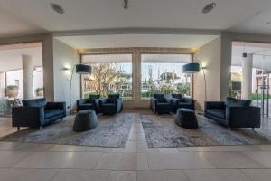 a lobby with couches and chairs and a large window at Hotel Isola Sacra Rome Airport in Fiumicino