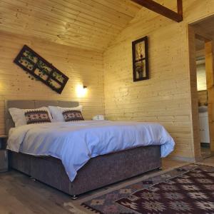 een slaapkamer met een groot bed in een houten muur bij Baltina Parc Transfagarasan in Curtea de Argeş