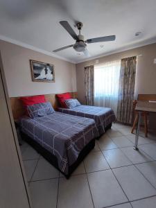 a bedroom with two beds and a ceiling fan at Villa Pesca Self Catering accommodation in Richards Bay