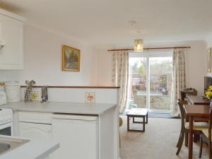 uma cozinha com armários brancos, uma mesa e uma janela em The Annexe em Newchurch