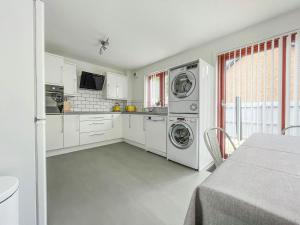 a kitchen with white cabinets and washing machines at Ceol Na Mara in Dornoch