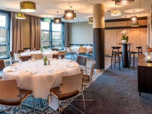 - une salle à manger avec des tables, des chaises et des fenêtres dans l'établissement Novotel Paris 14 Porte d'Orléans, à Paris