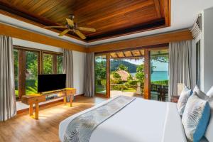Un dormitorio con una cama y un televisor y ventanas. en The Beach Natural Resort Koh Kood, en Ko Kood