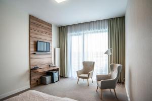 um quarto de hotel com duas cadeiras, uma secretária e uma televisão em Hotel Bonifacio SPA&SPORT Resort em Sochocin