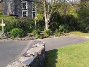 a driveway with a stone wall next to a house at Bronhaul in Llanbrynmair