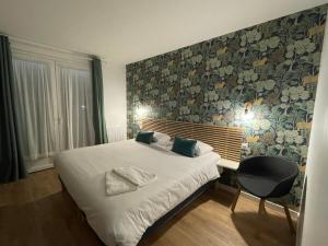 a bedroom with a bed and a wall with floral wallpaper at Hôtel des Dunes Noirmoutier in La Guérinière +61 photos