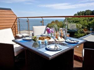 a table on a balcony with a view of the ocean at Dunlin 4 - The Cove in Brixham
