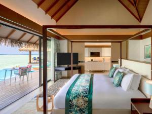 Pullman Maldives All-Inclusive Resort في Maamutaa: غرفة نوم مع سرير وإطلالة على المحيط