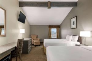 a hotel room with two beds and a chair at Travelodge by Wyndham Coffeyville in Coffeyville