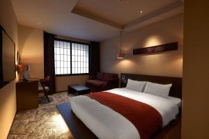 a hotel room with a large bed and a chair at Minn Kanazawa in Kanazawa