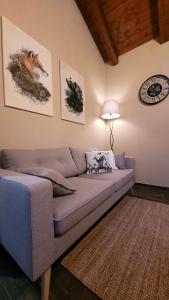BAITA LOVELY AND CENTRAL SAUZE D'OULX في ساوتسي دو اولكس: غرفة معيشة مع أريكة وساعة على الحائط