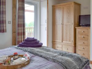 Cedar Lodge في Herstmonceux: غرفة نوم مع سرير وفوط أرجوانية عليه