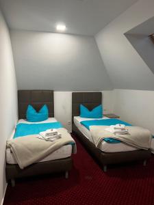 Duas camas individuais num quarto com almofadas azuis em Pension-Geli em Monplaisir