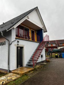 a white house with a red staircase on it at Pension-Geli in Monplaisir