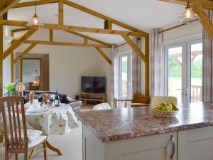 Cedar Lodge في Herstmonceux: مطبخ وغرفة معيشة مع طاولة مع وعاء من الفواكه