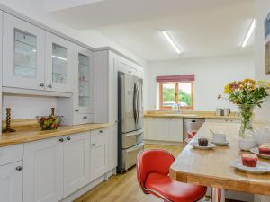 a kitchen with white cabinets and a wooden table at The Coach House in Upwell