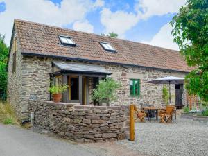 ein Steinhaus mit einem Tisch und einem Sonnenschirm in der Unterkunft The Cider Barn in Flaxley